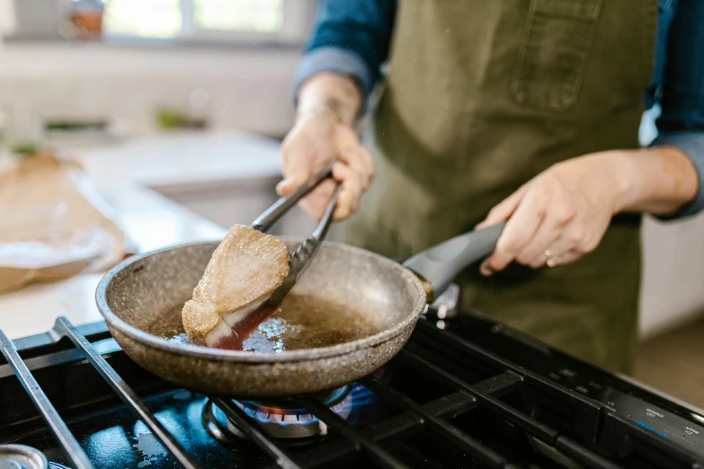 a person cooking food in a frying pan on a stove, by Joe Bowler, pexels, “ iron bark, chicken, laura watson, thumbnail