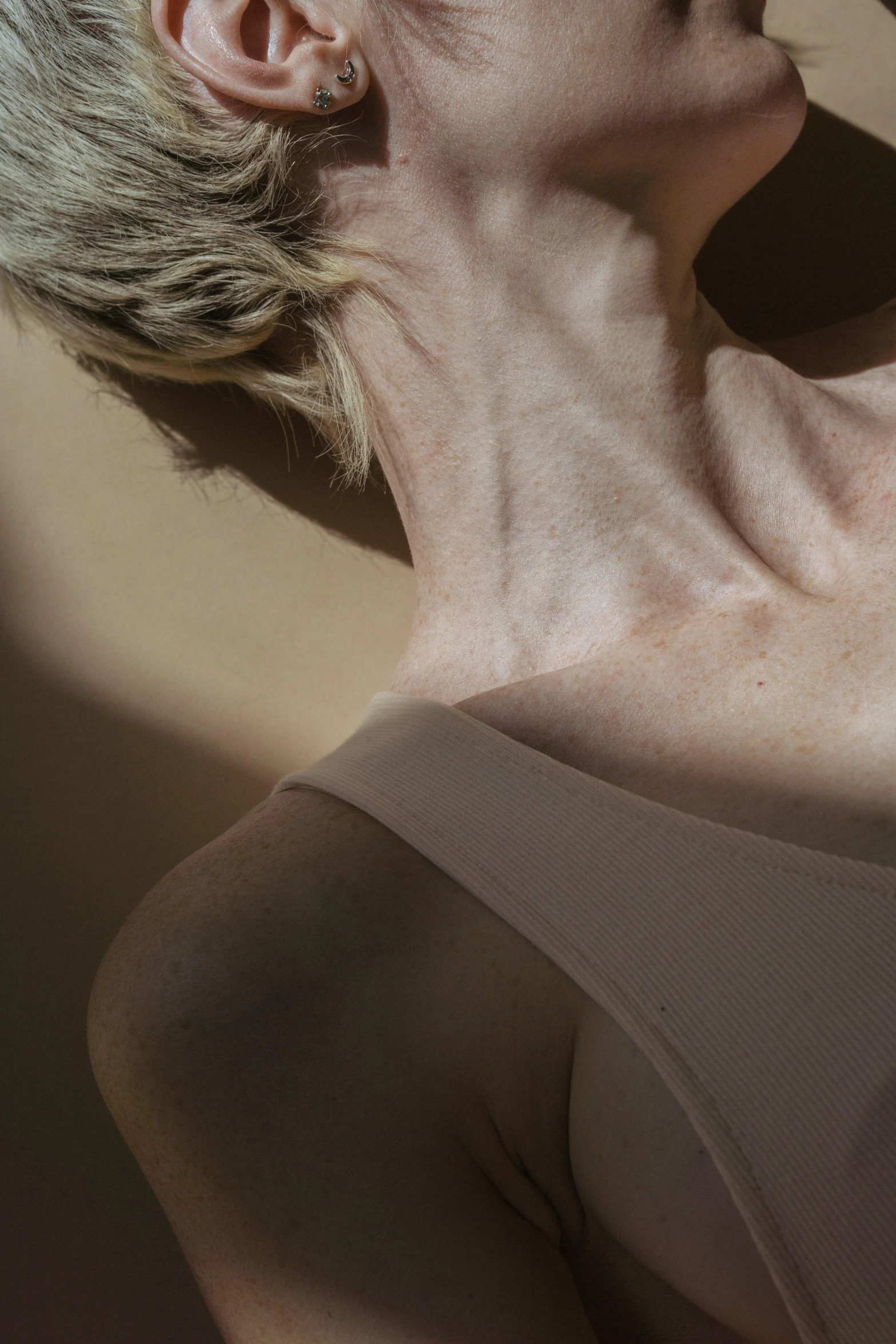 a woman holding a banana up to her face, an album cover, by Anna Boch, trending on pexels, hyperrealism, wrinkled muscles skin, ethereal back light, in elegant decollete, light tan