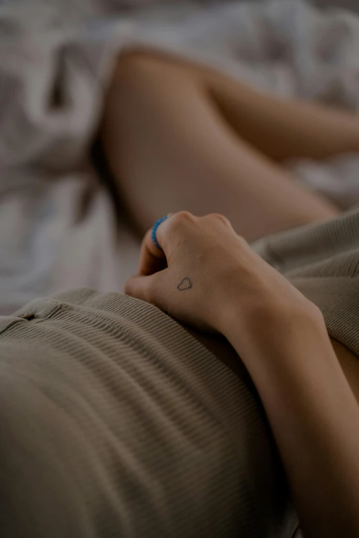 a close up of a person laying on a bed, a tattoo, flirting, zoomed out shot, hand on hip, comforting