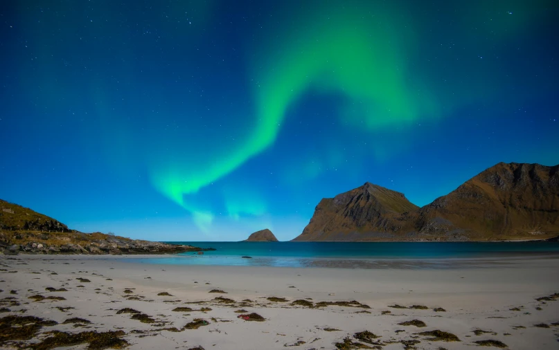 a beach with a body of water and mountains in the background, pexels contest winner, art nouveau, aurora borealis, archipelago, national geographics, blue and green light