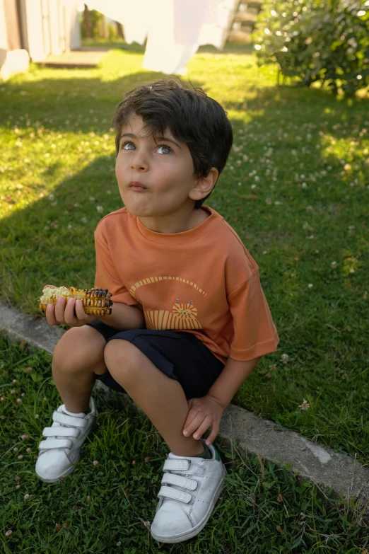 a young boy sitting in the grass eating corn, a picture, by Edward Avedisian, pexels contest winner, symbolism, tan skin a tee shirt and shorts, terracotta, lofi, profile pic