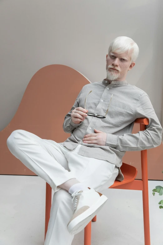 a man sitting in a chair next to a potted plant, inspired by Sigurd Swane, wearing off - white style, intense albino, wearing a linen shirt, kano)