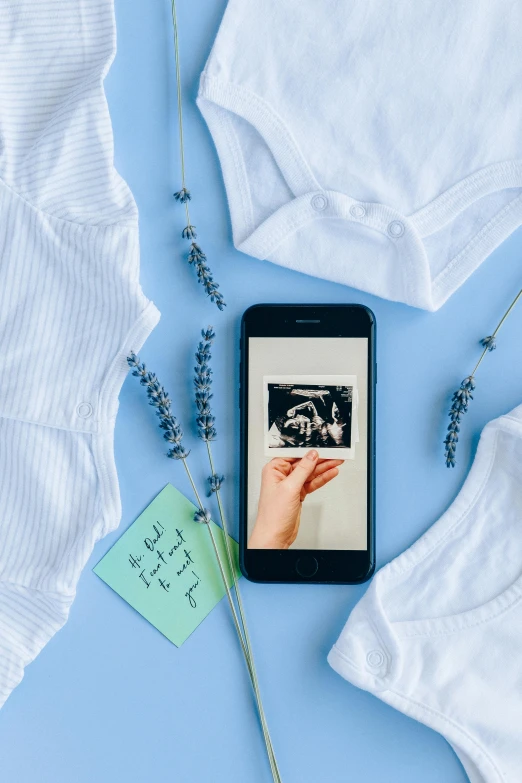 a cell phone sitting on top of a white shirt, a polaroid photo, by Julia Pishtar, pexels contest winner, conceptual art, pregnancy, black and blue and purple scheme, birth, on a canva