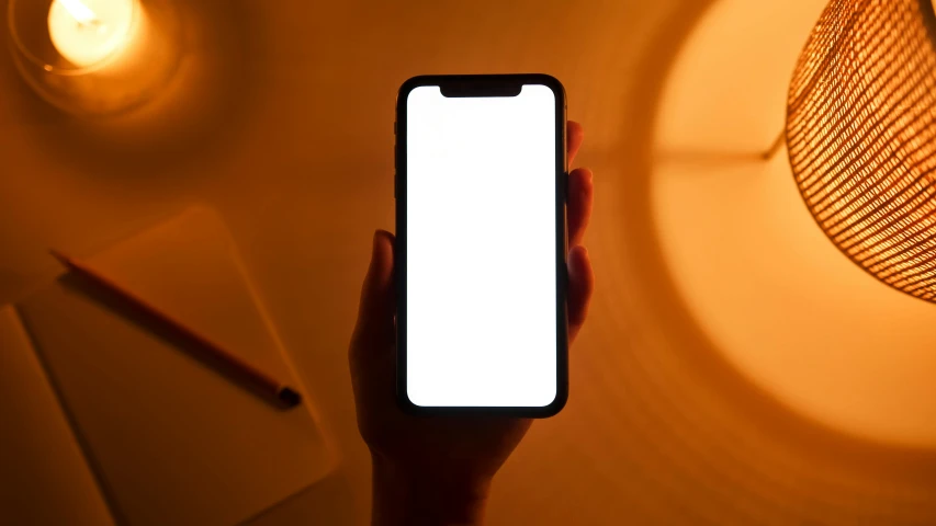 a person holding a cell phone with a white screen, by Carey Morris, pexels, bright internal glow, gradient brown to white, single light, rounded corners