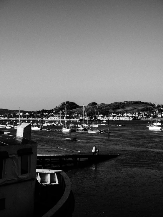 a black and white photo of a harbor filled with boats, a black and white photo, by Glennray Tutor, golden hour in pismo california, high contrast!!, hills, leica s photograph