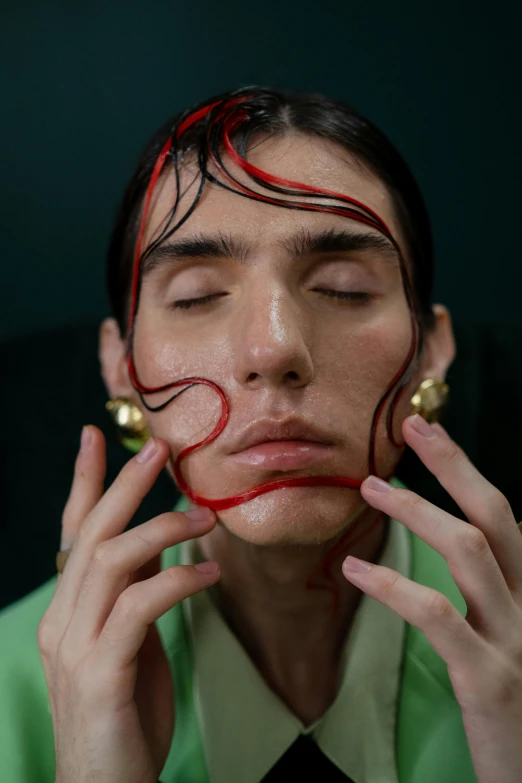 a close up of a person holding a cell phone to their face, an album cover, inspired by Yanjun Cheng, snakes in place of hair, nonbinary model, hans bellmer and nadav kander, red and green tones
