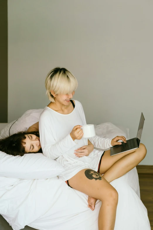 two women sitting on a bed with a laptop, inspired by Elsa Bleda, trending on pexels, white, flirting, sprawling, ying and yang