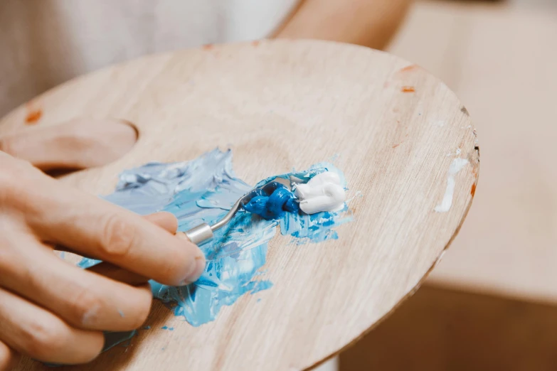 a close up of a person holding a paint palette, trending on pexels, arbeitsrat für kunst, blue white colors, on a wooden plate, children painting, scrape off