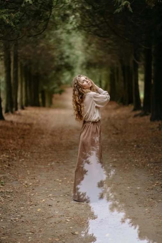 a woman standing in the middle of a forest, inspired by Oleg Oprisco, unsplash, renaissance, with long curly, streaks of dust, on forest path, modelling