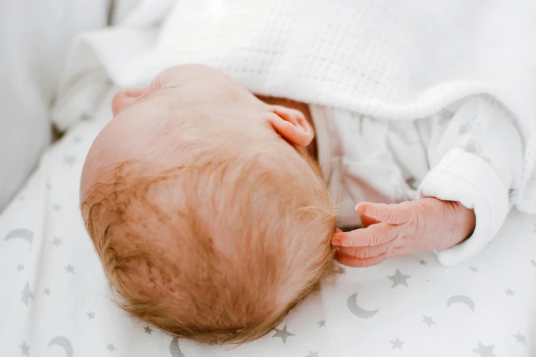 a close up of a baby laying on a bed, by Ruth Simpson, trending on pexels, happening, touching heads, tiny stars, white background, very handsome