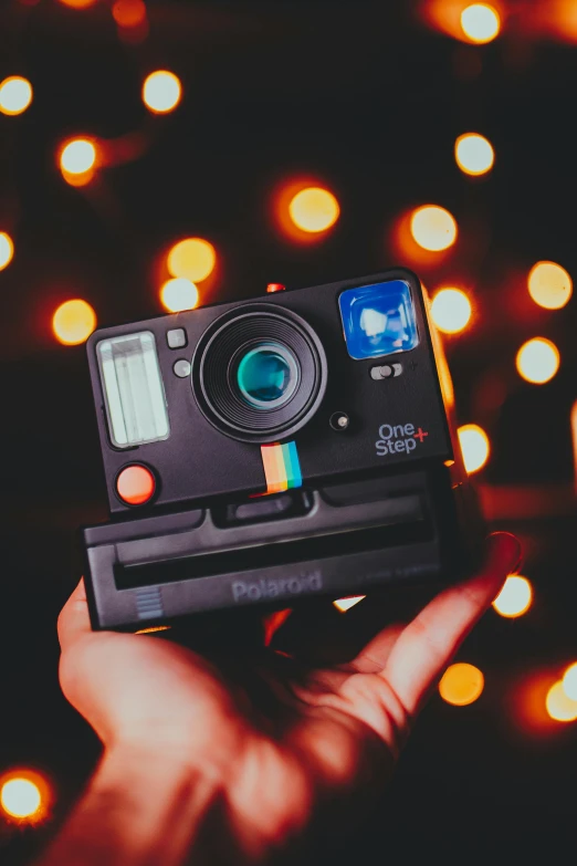 a person holding a polar camera in front of a christmas tree, a polaroid photo, inspired by Elsa Bleda, unsplash contest winner, holography, lights on, in front of an orange background, on black background, vhs effects