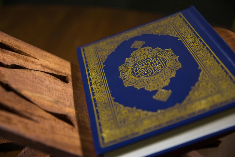 a blue book sitting on top of a wooden table, hurufiyya, thumbnail, mecca, brown, handcrafted