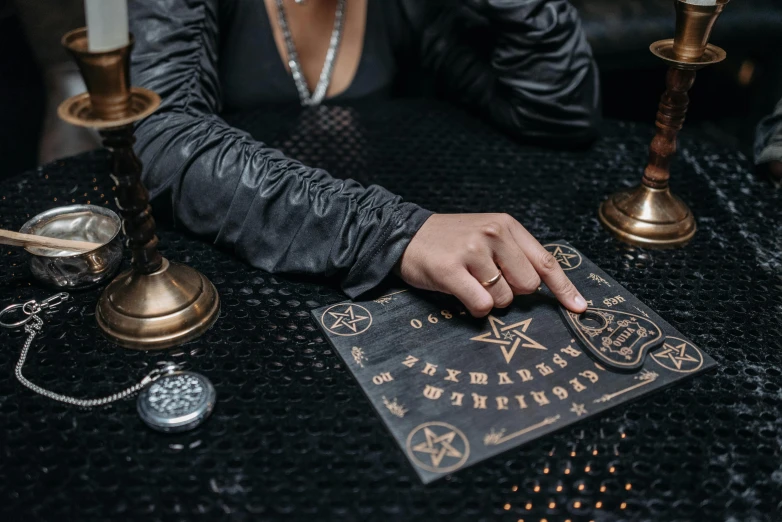 a close up of a person sitting at a table, trending on pexels, gothic art, summoning circle, instagram post, female magician, hieroglyphic occult