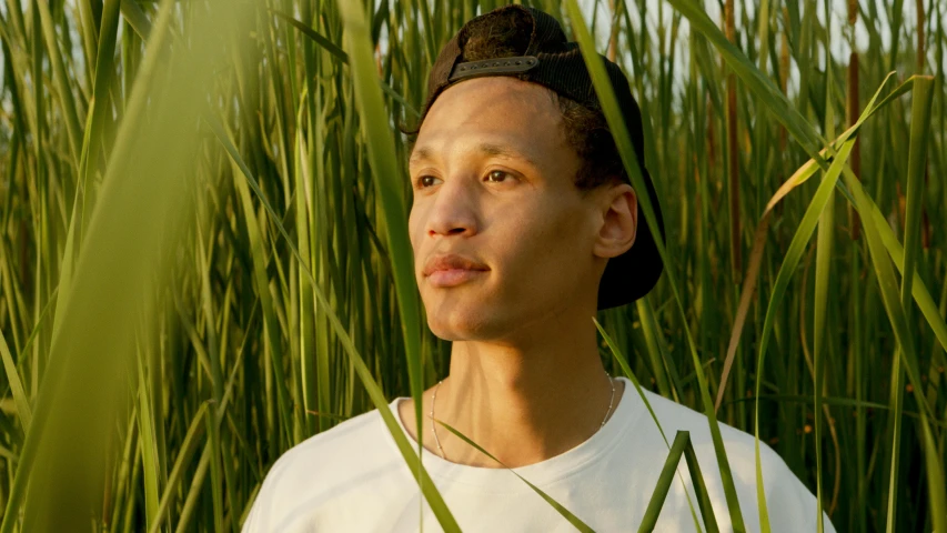 a man standing in a field of tall grass, perfectly lit face, raffael, around 1 9 years old, promotional photo