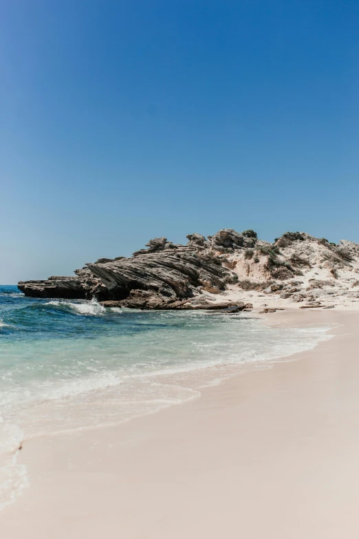 a man standing on top of a sandy beach next to the ocean, rock arcs, crystal clear blue water, whealan, al fresco