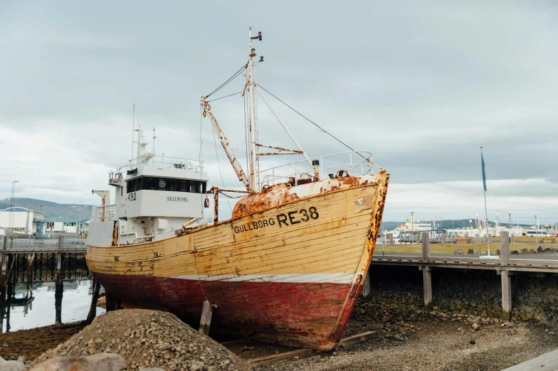 a boat sitting on top of a beach next to a dock, by Hallsteinn Sigurðsson, pexels contest winner, big graphic seiner ship, restoration, reykjavik, brown