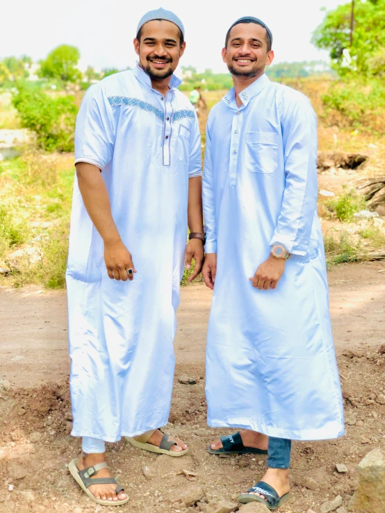 two men standing next to each other on a dirt road, instagram, dau-al-set, dressed thobe, pale blue outfit, thumbnail, sleepwear