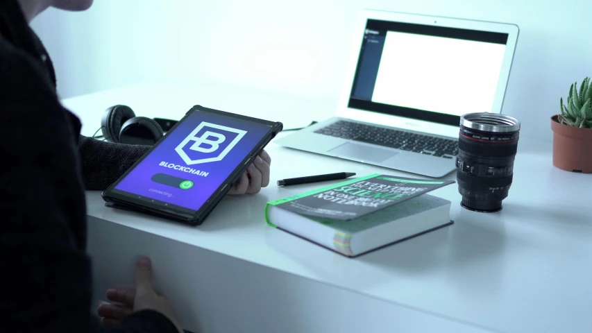 a person sitting at a desk with a laptop and a tablet, a hologram, behance contest winner, blockchain vault, b - roll, material design, 9 9 designs