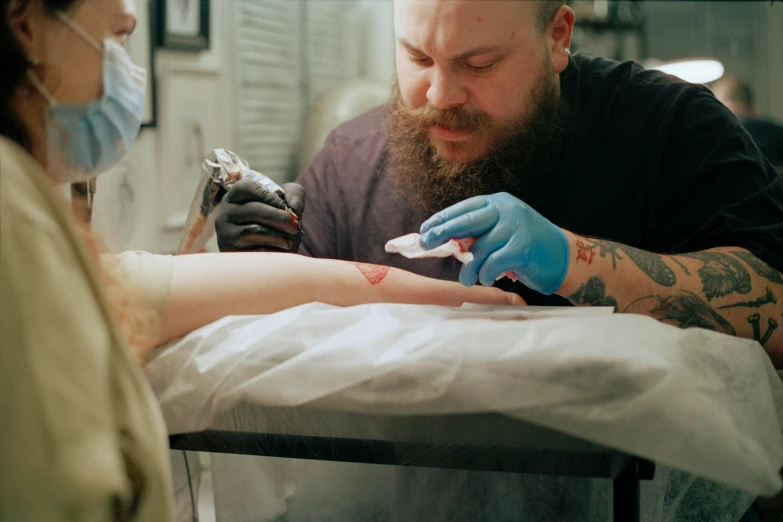 a man getting a tattoo on a woman's leg, a tattoo, by Lee Loughridge, pexels contest winner, hyperrealism, action bronson, ilustration, stick and poke, cinematic still