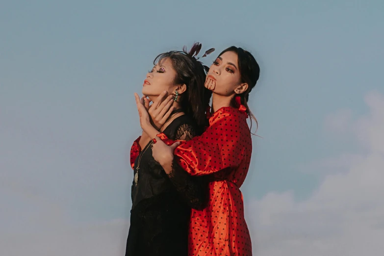 a couple of women standing next to each other, an album cover, trending on pexels, black and red silk clothing, looking to the sky, portrait n - 9, jewelry