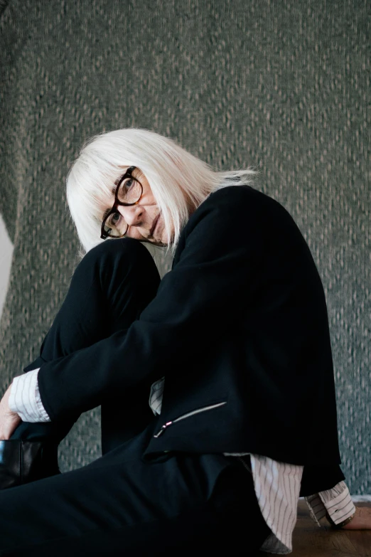 a woman with white hair and glasses sitting on the floor, inspired by Cindy Sherman, trending on unsplash, altermodern, in a black suit, musician, in square-rimmed glasses, grain”