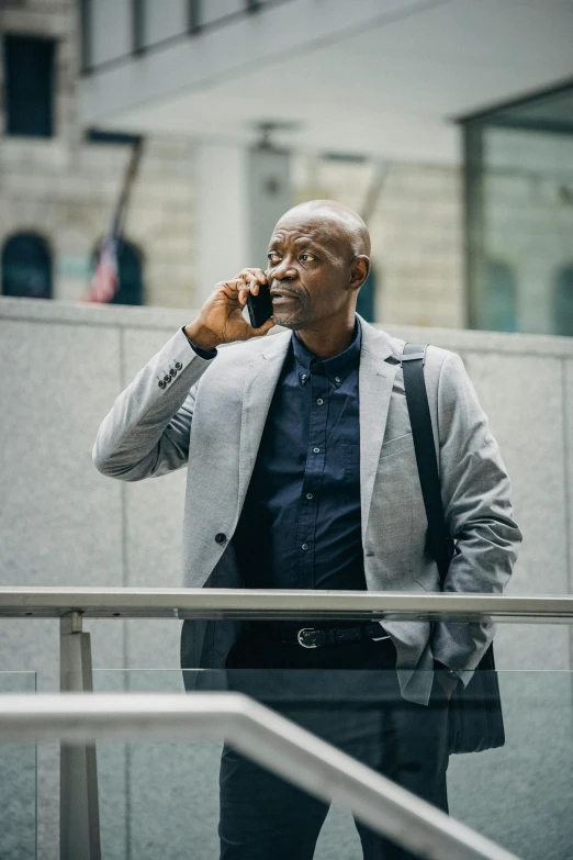 a man in a suit talking on a cell phone, pexels contest winner, samuel jackson, atiba jefferson, professionally color graded, people walking around