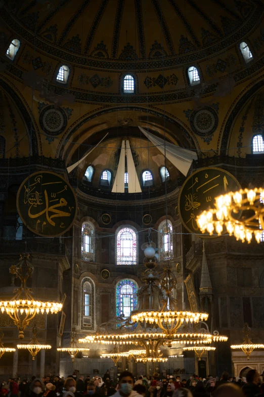 a large group of people inside of a building, a mosaic, arabesque, black domes and spires, church chandelier, byzantine, minarets