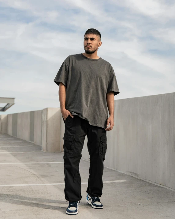 a man standing in a parking lot with a skateboard, inspired by Wang E, unsplash, renaissance, wearing cargo pants, wearing a black tshirt, dark washed tint black, full - body - front - shot