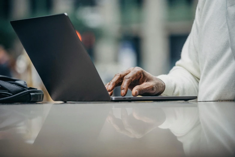 a close up of a person typing on a laptop, by Carey Morris, afro tech, street life, thumbnail, sitting on a table