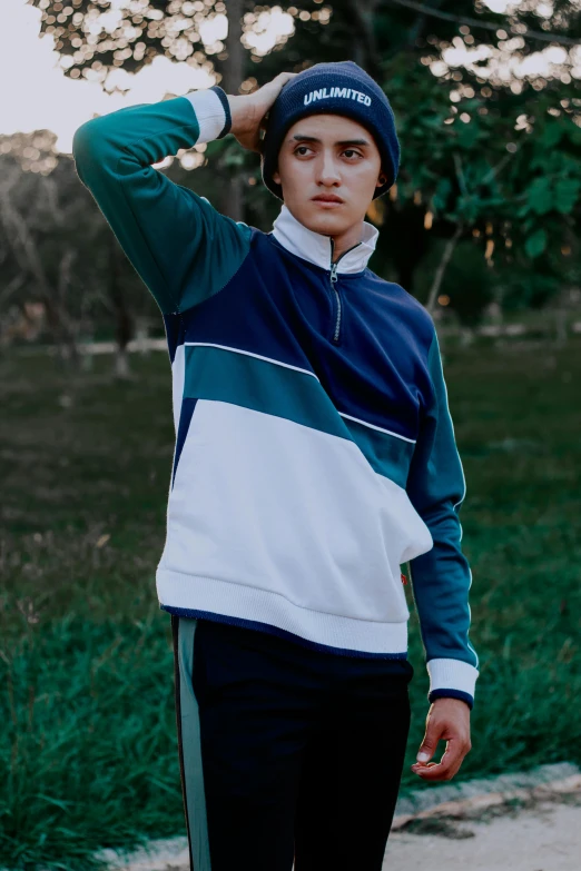a man standing next to a skateboard on a sidewalk, a colorized photo, by Matija Jama, unsplash, renaissance, wearing a track suit, portrait androgynous girl, gradient white blue green, blue turtleneck