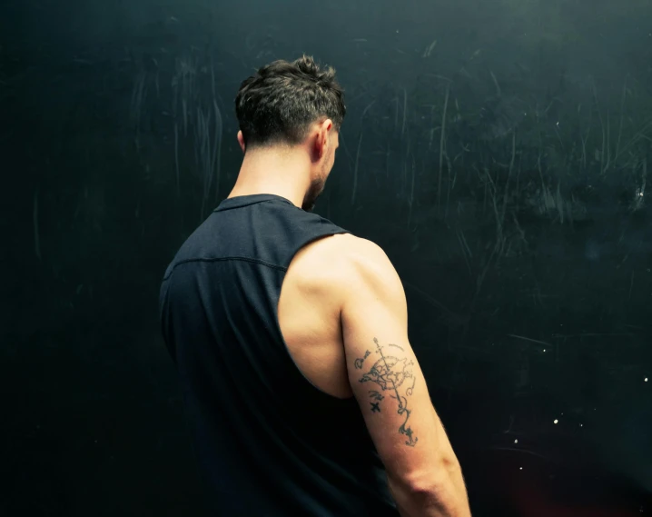 a man standing in front of a blackboard with writing on it, a tattoo, pexels contest winner, in a gym, profile image, back tattoo, vascularity