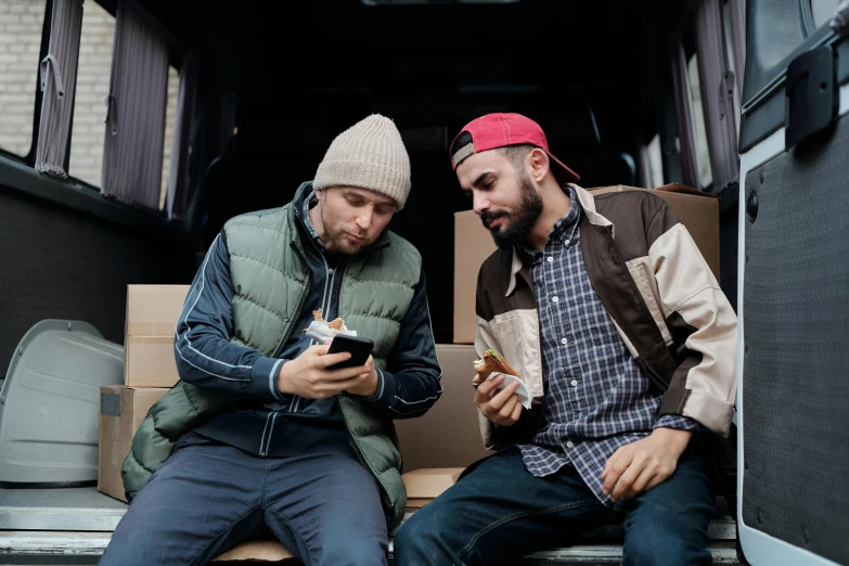 two men sitting in the back of a van looking at their cell phones, trending on pexels, middle eastern style vendors, avatar image, mac miller, inspect in inventory image