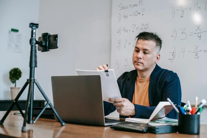 a man sitting at a desk in front of a laptop, pexels contest winner, academic art, teacher, holding a clipboard, sitting in front of a microphone, everything fits on the screen