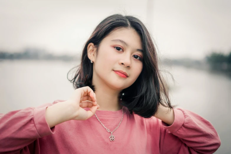 a woman standing in front of a body of water, a picture, inspired by Kim Jeong-hui, pexels contest winner, realism, young cute wan asian face, wearing jewellery, smol, pink
