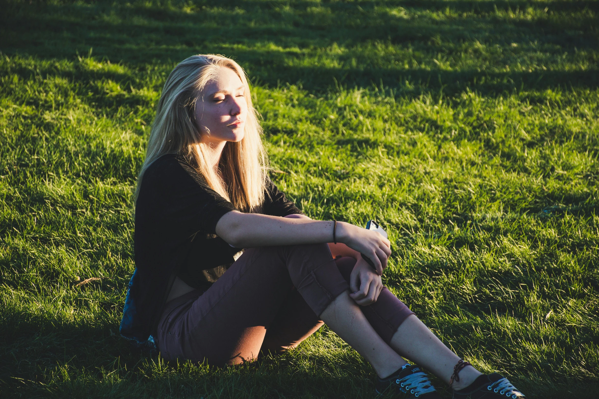 a woman sitting on top of a lush green field, a girl with blonde hair, low - lighting, profile picture 1024px, high contrast backlight