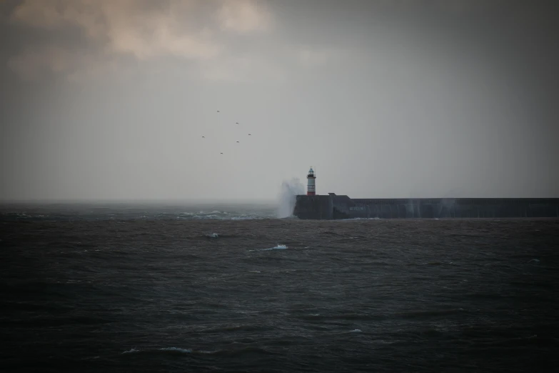 a lighthouse in the middle of a body of water, happening, maryport, atmospheric photograph, 2022 photograph, grey