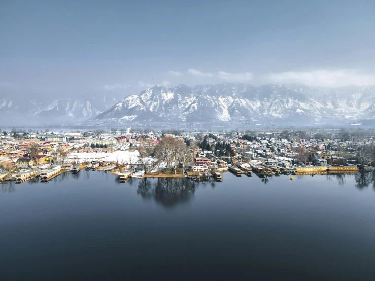 a large body of water surrounded by snow covered mountains, a tilt shift photo, floating buildings, drone footage, india, high quality product image”