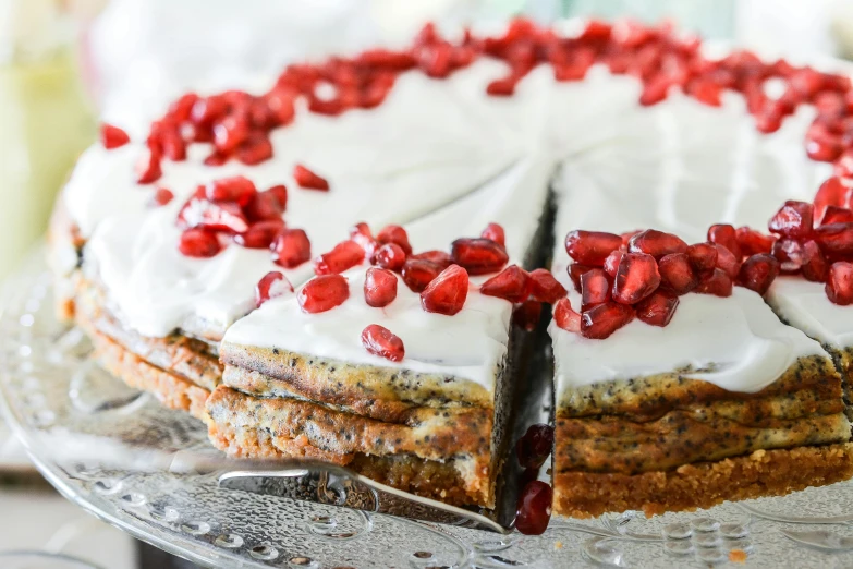 a cake with white frosting and pomegranates on top, healthy, poppy, torri, crisp edges