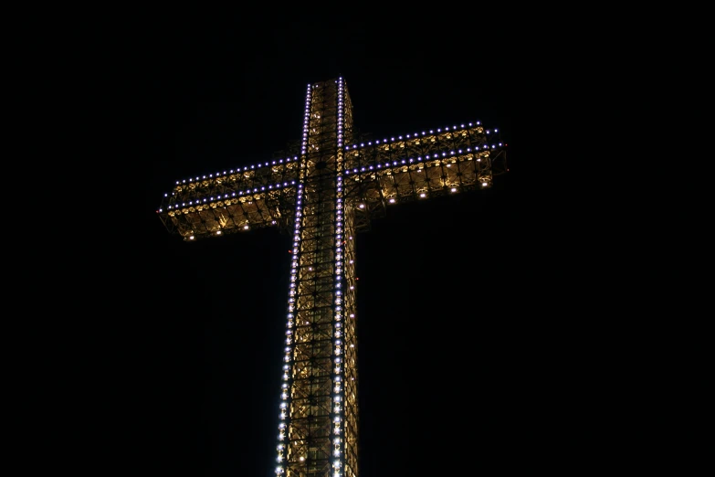 a large cross is lit up at night, view from bottom to top, square, shot with sony alpha 1 camera, profile image