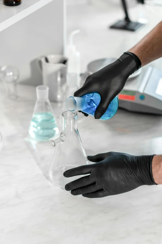 a person in black gloves holding a beaker filled with liquid, leather gloves, hands on counter, soft iridescent membranes, thumbnail