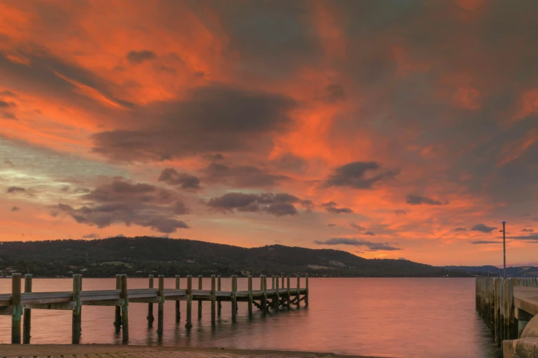 a pier that is next to a body of water, pexels contest winner, romanticism, red clouds, lachlan bailey, panoramic shot, brown