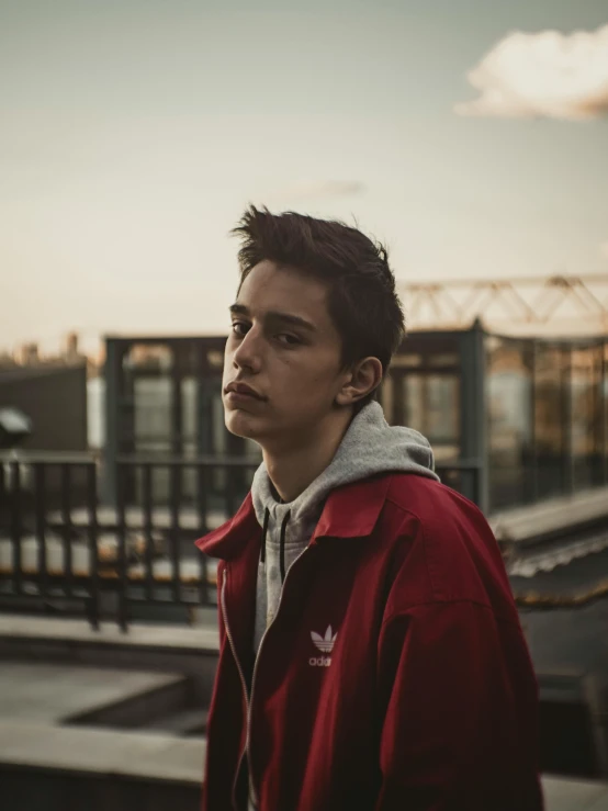 a young man standing on top of a roof, an album cover, pexels contest winner, realism, androgynous face, wearing red jacket, headshot profile picture, low light cinematic