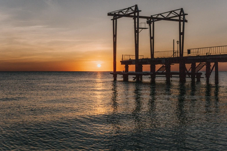 a pier in the middle of the ocean at sunset, pexels contest winner, rusty metal towers, red sea, high detailed photo, industrial photography