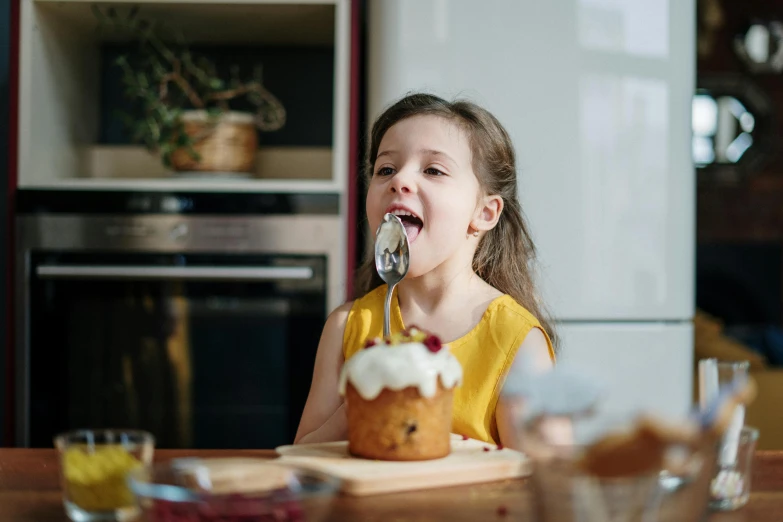 a little girl sitting at a table with a piece of cake in her mouth, pexels contest winner, cooking, manuka, avatar image, spoon placed