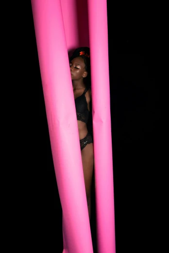 a woman standing behind pink poles in the dark, inspired by Bert Stern, inflatable, lupita nyong'o, [ floating ]!!, club photography