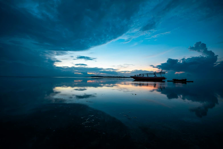 a boat sitting on top of a body of water, by Daniel Seghers, unsplash contest winner, under blue clouds, calm evening, indonesia national geographic, mirror like water