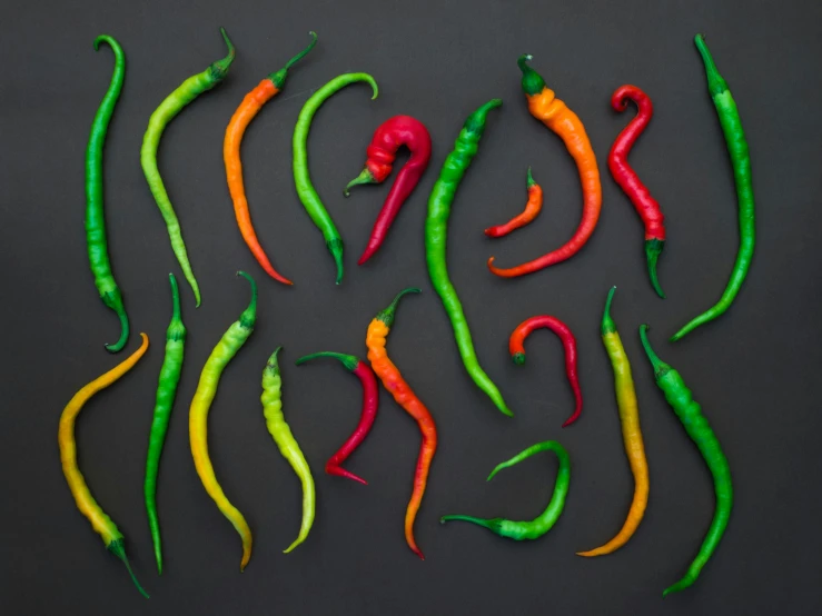 a bunch of hot peppers sitting on top of a table, a digital rendering, inspired by Albert Joseph Pénot, trending on pexels, background image, scale model photography, multicolored, a high angle shot