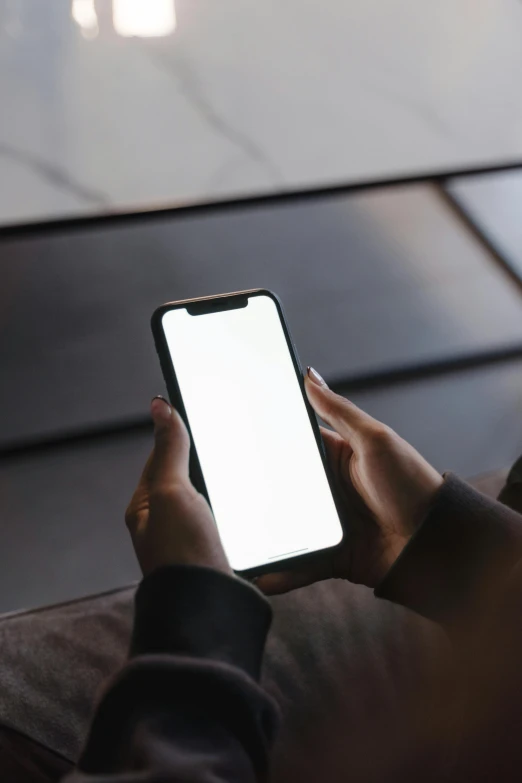 a person sitting on a couch holding a cell phone, trending on pexels, blank, professional iphone photo, dark. no text, corporate phone app icon