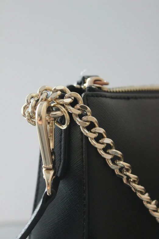 a black purse sitting on top of a table, by Robbie Trevino, unsplash, wearing a gold chain, high detailed close up of, zippers, product view