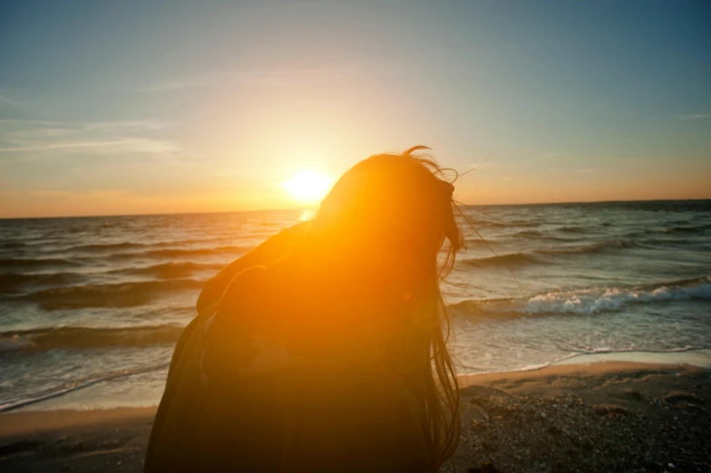 a woman standing on top of a beach next to the ocean, pexels contest winner, romanticism, flowing backlit hair, blocking the sun, upset, closeup photograph